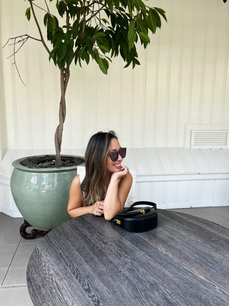 Jenn sitting and smiling with a handbag next to her on a table.