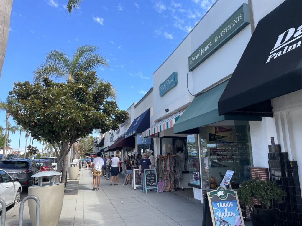 Stores line up the streets of Orange Ave in Coronado with shoppers on the sidewalk.
