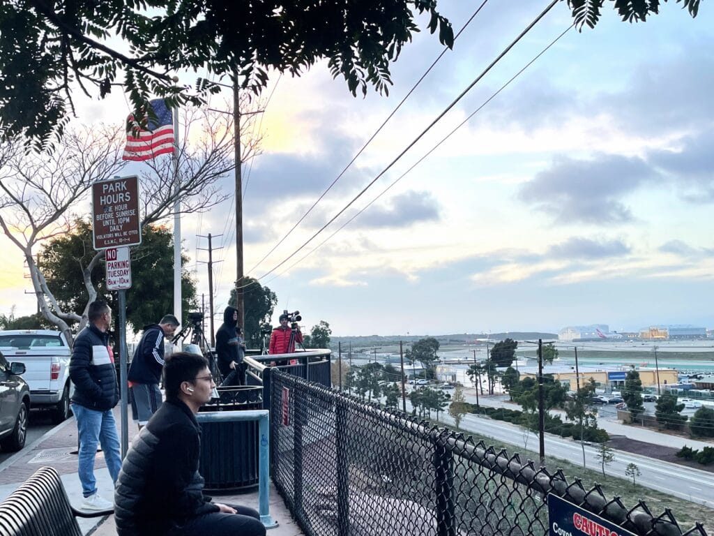Photographers and onlookers sit at a bench at Clutter Park.