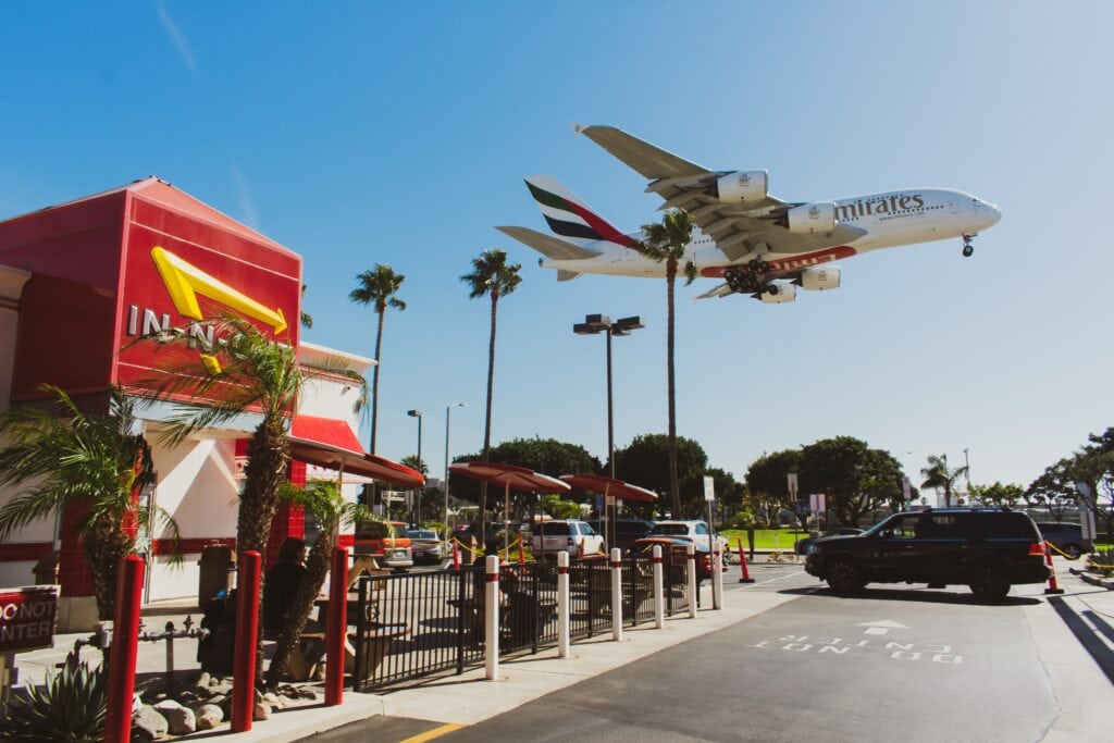 An Emirates Airplane landing at LAX and flying over In-N-Out.
