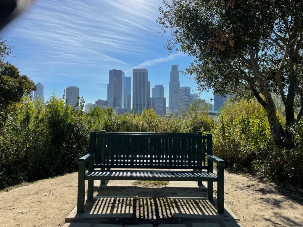Two green benches overlooking the DTLA skyline.