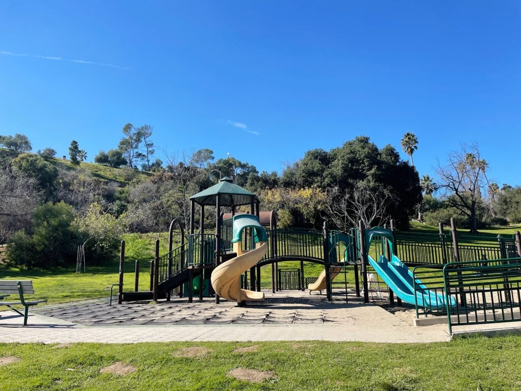 A green, beige and black play structure for kids in the middle of Elysian Park.