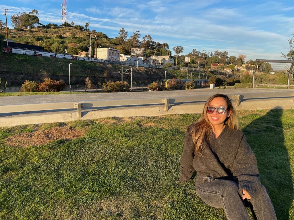 Jenn at the LA State Historic Park sitting on grass overlooking the scenic view.