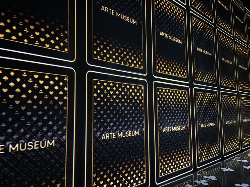 black and gold deck of cards displayed on a screen with the words Arte Museum on them.