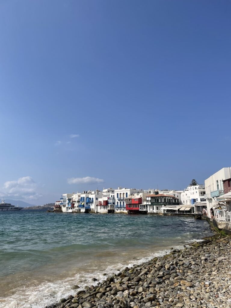 Homes line up the beach of Mykonos called "Little Venice" as the ocean waves crash on the shore.